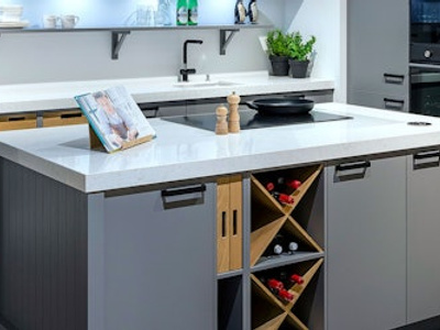 Strakke grijze showroom eilandkeuken met houten elementen