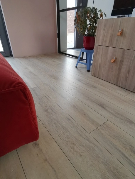 een kamer met houten vloer en rode bank