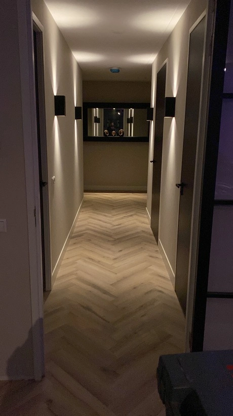 lang en smal verlichte gang met houten vloer