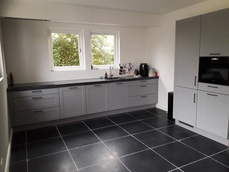 moderne keuken met grijze kasten en zwarte vloer