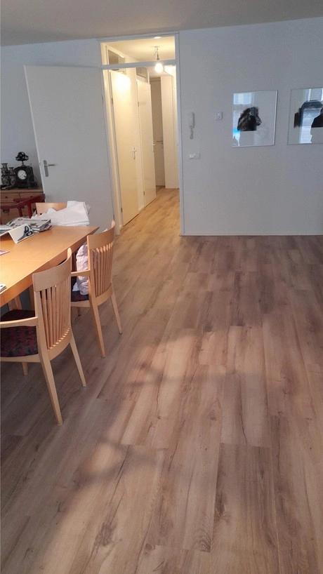 eetkamer met houten vloer en ganggang zichtbaar