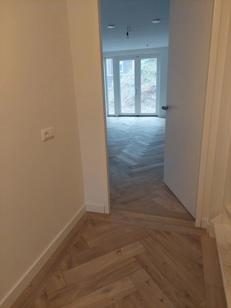 houten vloeren in visgraatpatroon zichtbaar door deur