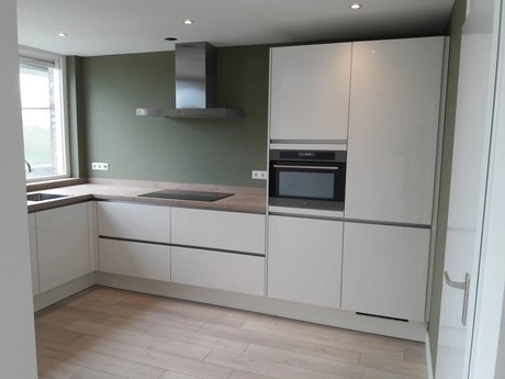 moderne keuken met witte kasten en groen muur