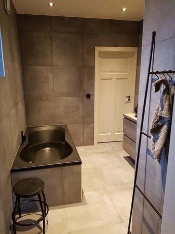 moderne badkamer met grijze tegels en badkuip