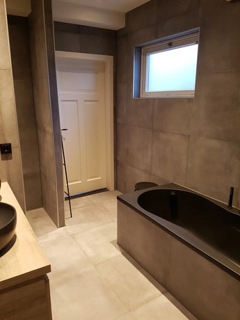 moderne badkamer met grijze tegels en badkuip