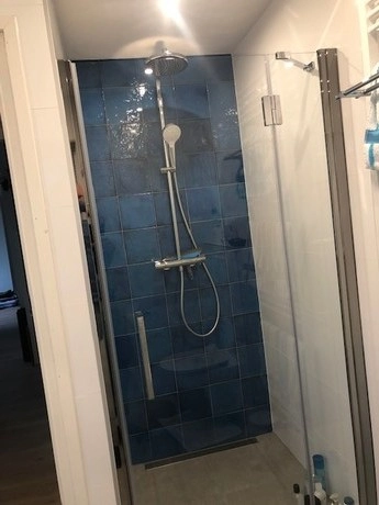 moderne douche met blauwe tegelwand en glazen deur