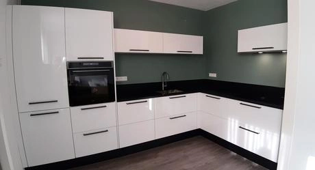 moderne keuken met witte kasten en groen muur