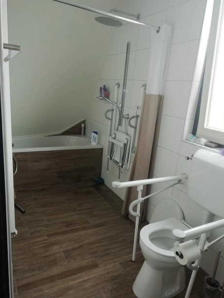 badkamer met bad en toilet met beugels