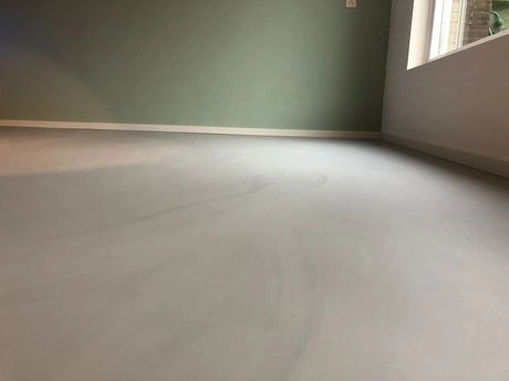glad afgewerkte gietvloer in een lichte kamer