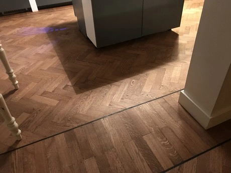 houten vloer met visgraatpatroon in warme verlichting