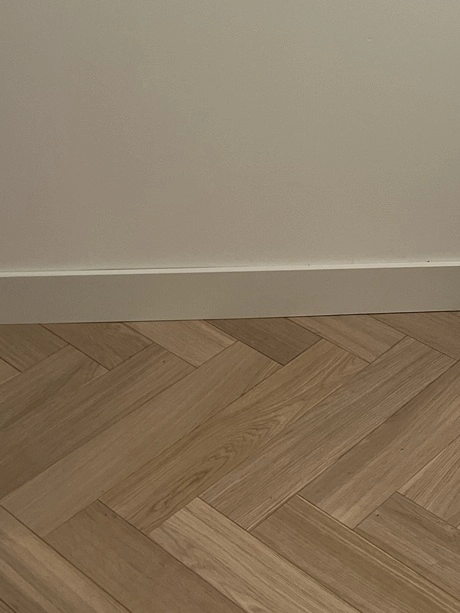 visgraatpatroon houten vloer naast een muur