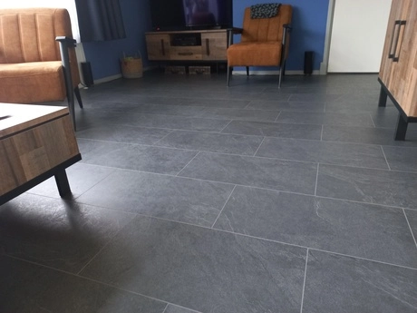woonkamer met grijze tegelvloer en houten meubels