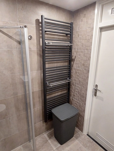 badkamer met radiator en prullenbak naast douche