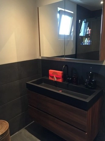 donkere badkamer met wastafel en grote spiegel