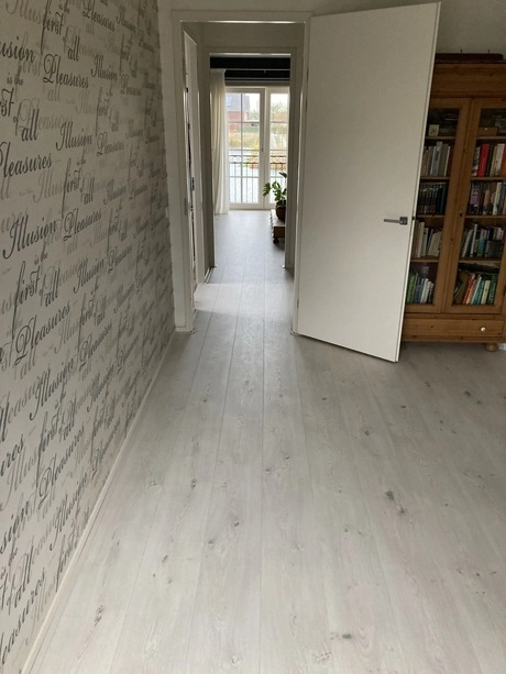 witte gang met boeken kast en geopende deur