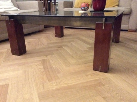 houten vloer met visgraatpatroon onder glazen tafel