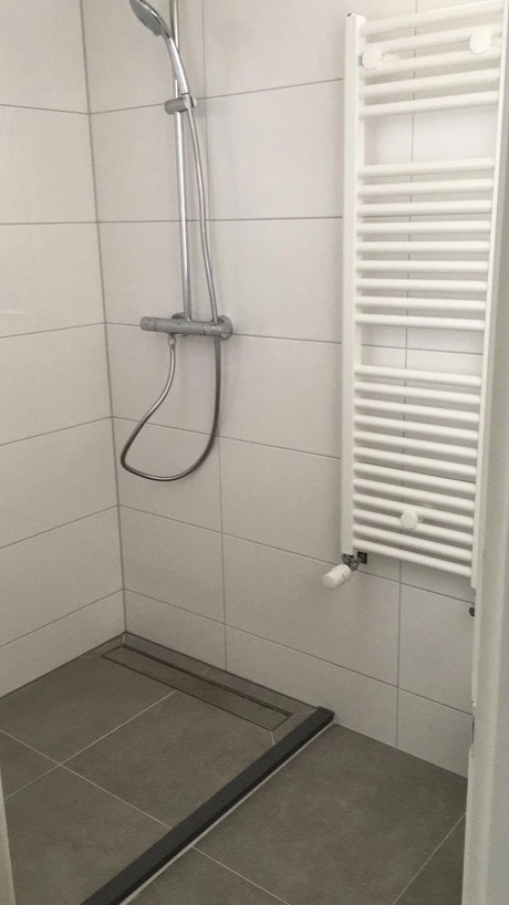 moderne douche met witte tegels en radiator