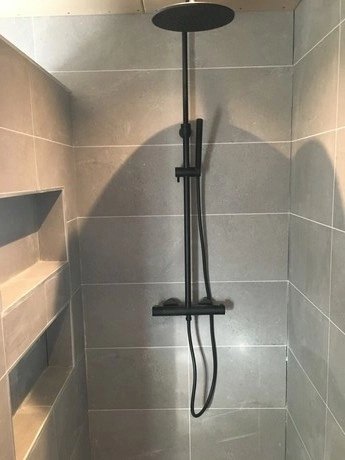 donkere regendouche in moderne betegelde badkamer