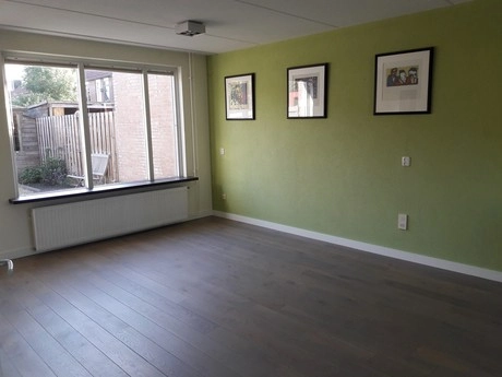 lege kamer met groene muur en drie schilderijen