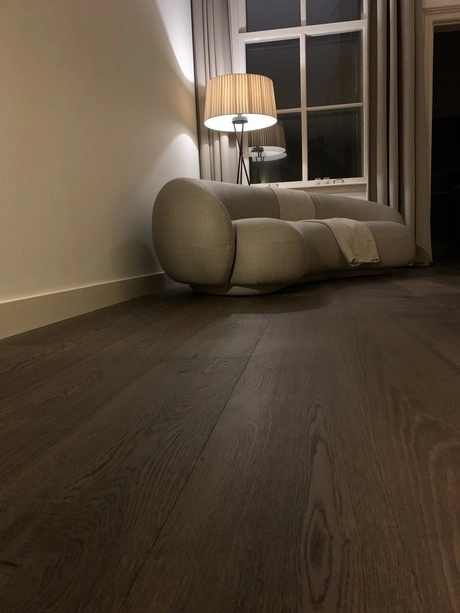 donkere houten vloer naast comfortabele bank