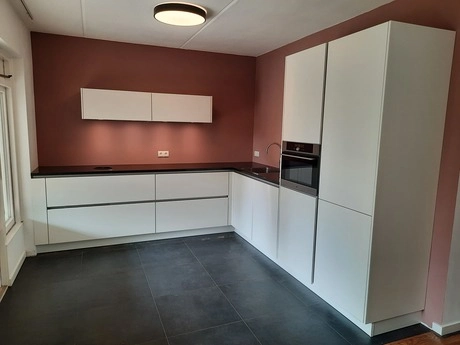 moderne keuken met witte kasten en donkere vloer