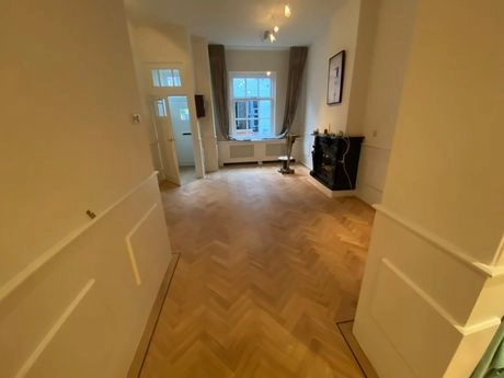 houten vloer in lichte woonkamer met haard