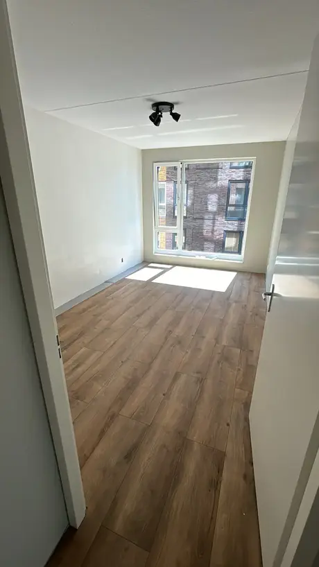 lege kamer met een houten vloer en raam