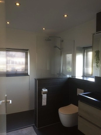 moderne badkamer met donkere tegels en douche