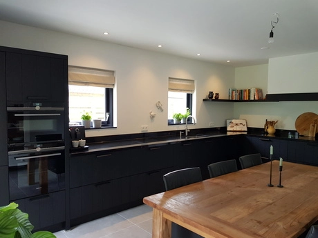 moderne keuken met donkere kasten en houten tafel