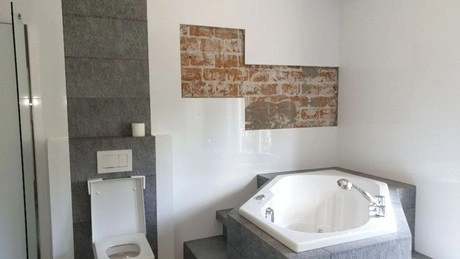 badkamer met bubbelbad en bakstenen muur