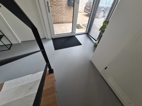 grijze gietvloer in moderne entreehal met trap
