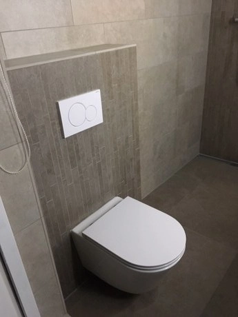 wandtoilet tegen beige betegelde muur gemonteerd