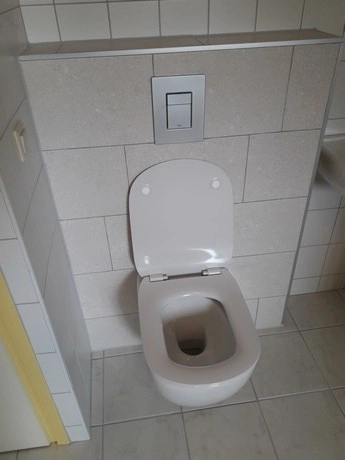 wit toiletpot tegen een betegelde muur