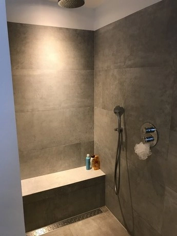 moderne douche met grijze tegels en hoekbank