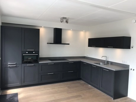 moderne keuken met zwarte kasten en apparatuur