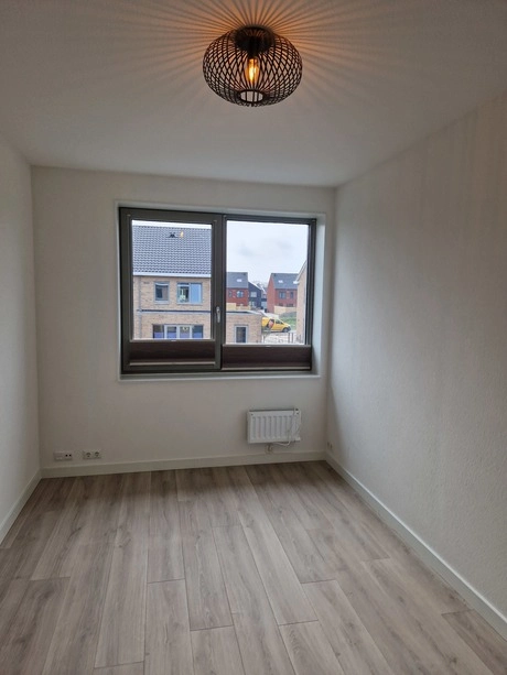 kleine lege kamer met raam en houten vloer