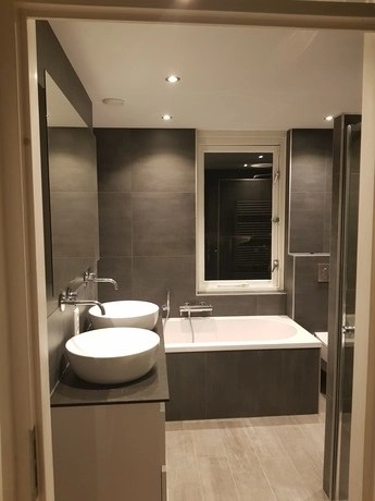 moderne badkamer met grijze tegels en badkuip