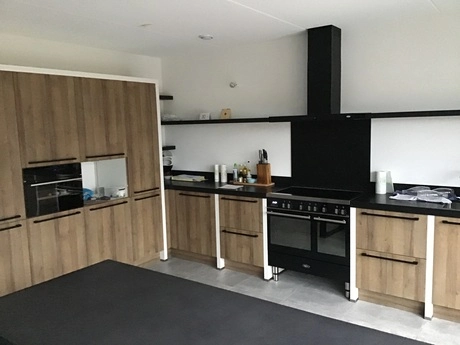moderne keuken met houten kasten en zwarte oven