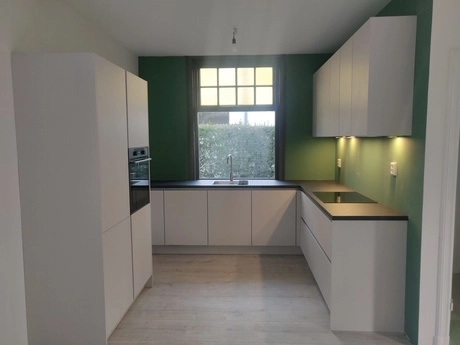moderne keuken met witte kasten en groene muren