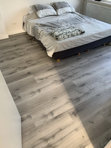 netjes opgemaakt bed houten vloer zonlicht aanwezig