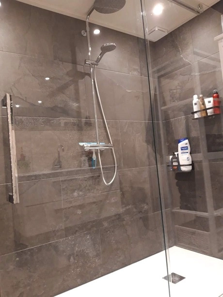 stijlvolle douche met glazen wand en shampooflessen