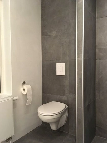 moderne badkamer met zwevend toilet en grijze tegels