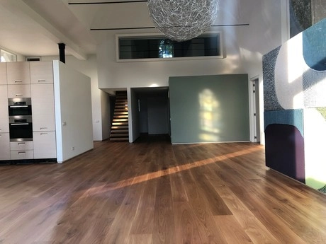 ruime woonkamer met houten vloer en keuken