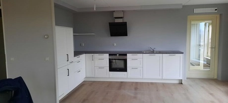 witte keuken met moderne apparatuur en houten vloer