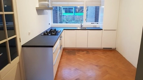 moderne keuken met zwart aanrecht en houten vloer
